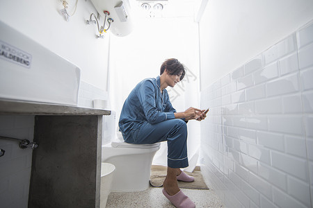 马桶家庭男生在厕所里看手机背景