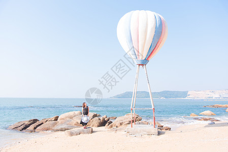 海边热气球旁聆听大海声音的女模特高清图片