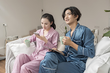 情侣在客厅休息玩手机平板电脑图片