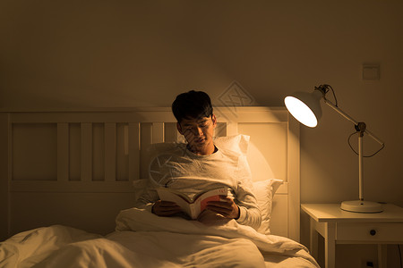 坐着睡睡前坐在床上看书的男生背景