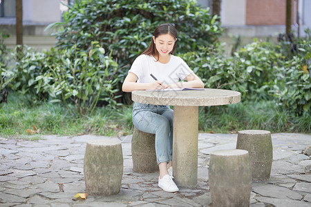 校园里坐在石凳上读书写字的女生图片