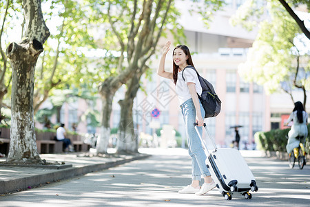 校园里拖着行李箱的女生背景图片