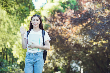 背着书包招招手打招呼的同学校园里背着书包抱着书的同学背景