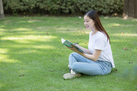 拿着课本坐在草坪上看书的大学生图片