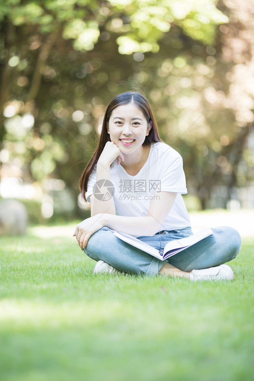 愉快地坐在草坪上学习的女同学图片
