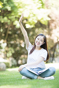 愉快地坐在草坪上学习的女同学图片