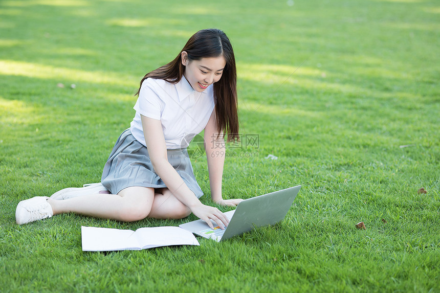 坐在草坪上使用笔记本电脑的同学图片