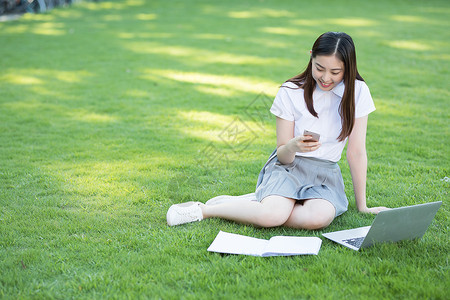 坐在草坪上的打电话的女生图片