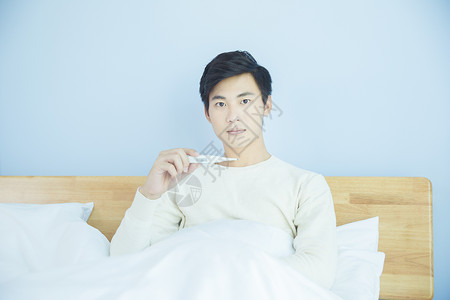 躺床上测量体温的年轻男性高清图片
