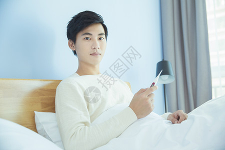 躺床上测量体温的年轻男性图片