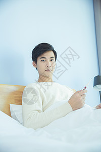 躺床上测量体温的年轻男性图片
