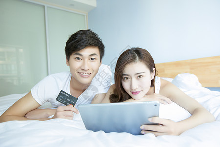 年轻情侣在床上网购背景图片