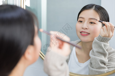 美女画眉站在镜子前画眉的年轻女性背景