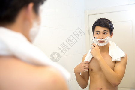年轻男子在浴室剃须图片