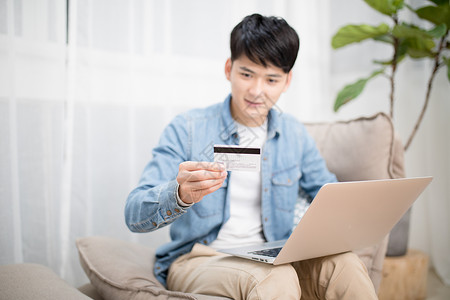 信用卡使用拿着银行卡使用电脑网购的男性背景