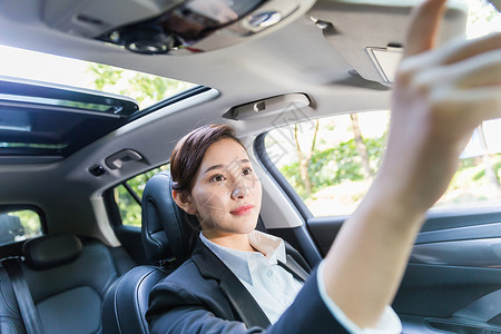 在开车的人商务女性在调整后视镜背景