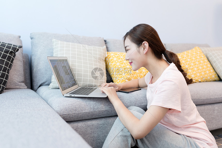 年轻美女靠着沙发玩电脑图片