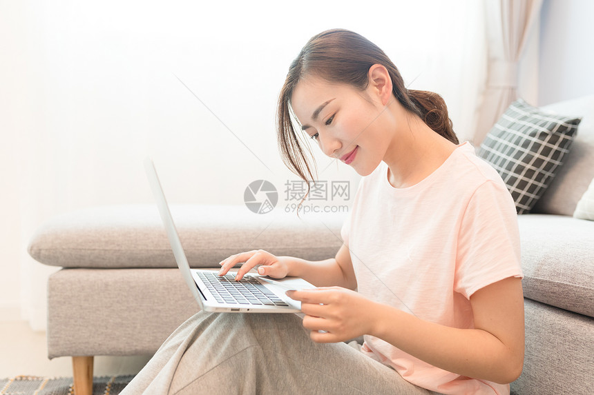 年轻美女靠着沙发玩电脑图片