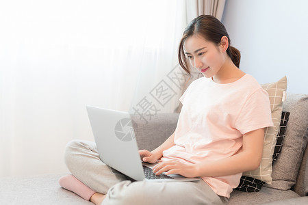 坐在沙发上玩电脑的年轻女性高清图片