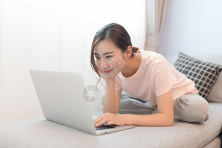 坐在沙发上玩电脑的年轻女性背景图片