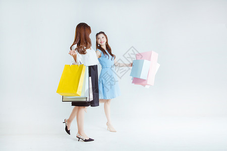 闺蜜手拎购物袋逛街棚拍图片