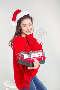手拿礼物盒的圣诞装扮女性棚拍背景图片