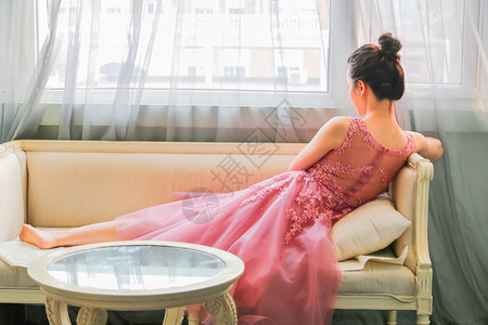 好看的窗帘坐在沙发上的优雅女生背影背景