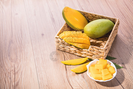 黄牛百叶片新鲜的芒果在木桌子上的果篮里背景