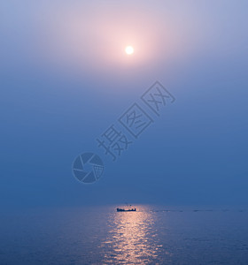 蓝色光辉光芒海上日出光影里的渔船背景