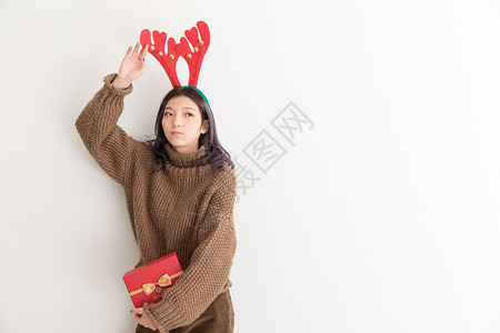 手拿礼盒带着鹿角的圣诞女性人像背景图片