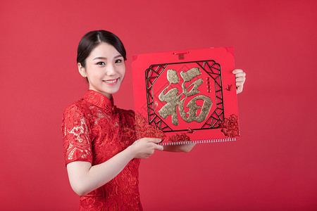 春节穿旗袍的女孩手拿福字图片