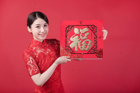 春节穿旗袍的女孩手拿福字高清图片