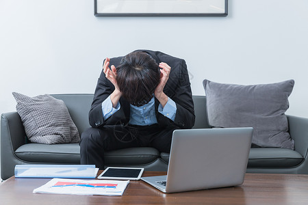 办公室内商务男士使用平板电脑痛苦抱头的商务男士背景