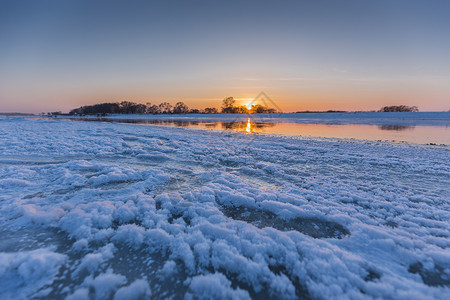 冬天结冰河流上的日出背景图片