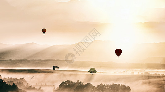 清晨阳光和白雾中的缓缓上升的热气球高清图片