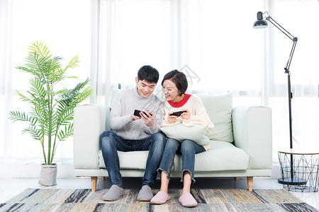 情侣手机玩游戏年轻情侣在客厅玩手机游戏背景