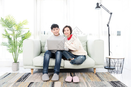 情侣一起玩电脑一起坐在沙发上玩电脑的情侣背景