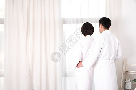 情侣穿着浴袍站在窗边高清图片