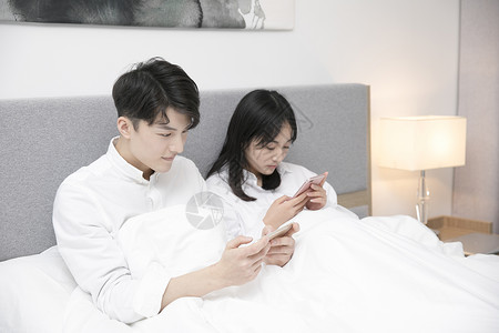 情侣在床上玩手机背景图片