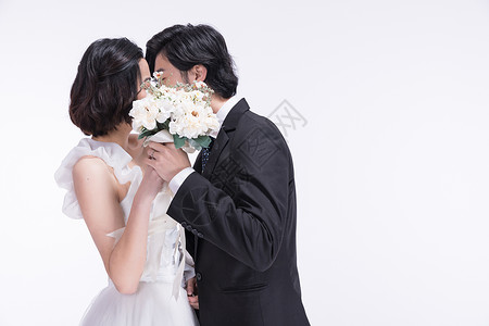 亚洲新娘身着西式礼服的年轻夫妻接吻背景