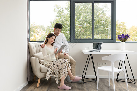 擦地女孩年轻夫妻幸福地坐在沙发上看平板电脑背景