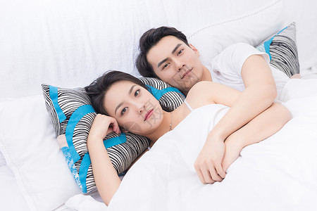 年轻夫妻拥抱躺床上休息图片
