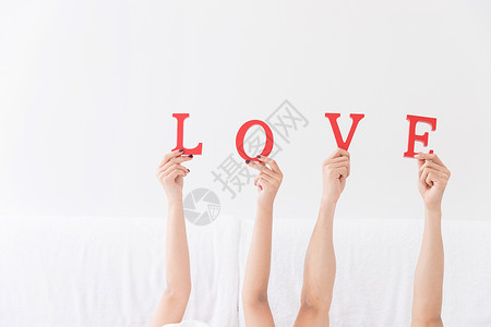 情侣三个素材年轻夫妻躺床上手拿LOVE特写背景