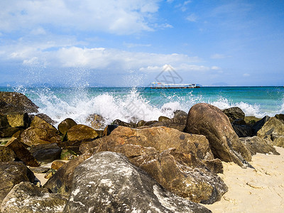 波浪光浪花拍打着海滩边的巨石背景