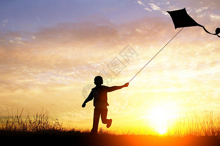 草地黄昏黄昏下放风筝的男孩设计图片