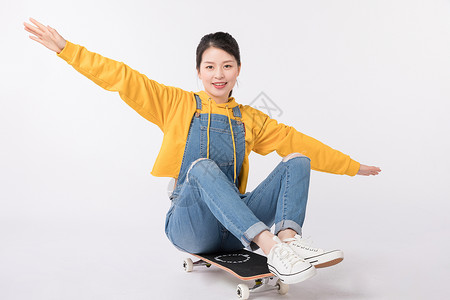 坐在滑板上欢呼的年轻女生背景图片