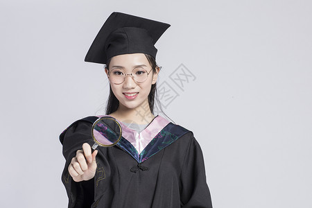 拿着放大镜的毕业女大学生图片