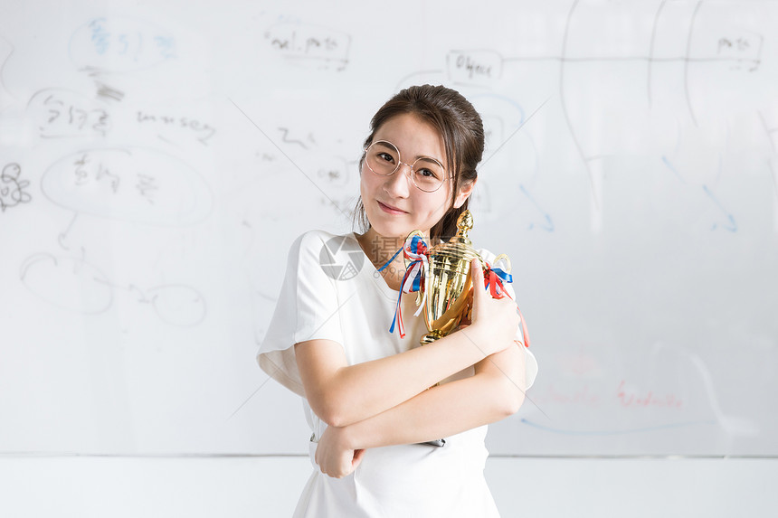 白板前手拿奖杯的大学生图片