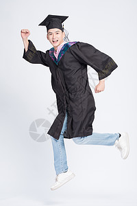跳跃学士服男孩跳跃的毕业大学生背景