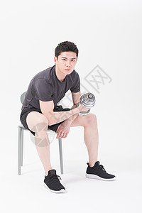 青年男性坐椅子上举哑铃健身图片